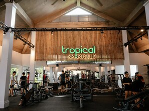 Un gimnasio con diversos equipos de ejercicio y un cartel que dice "tropical sportclub".