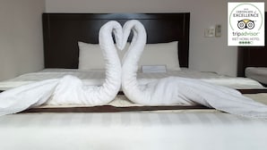 Habitación de hotel con una cama y una decoración de toallas con forma de dos cisnes.