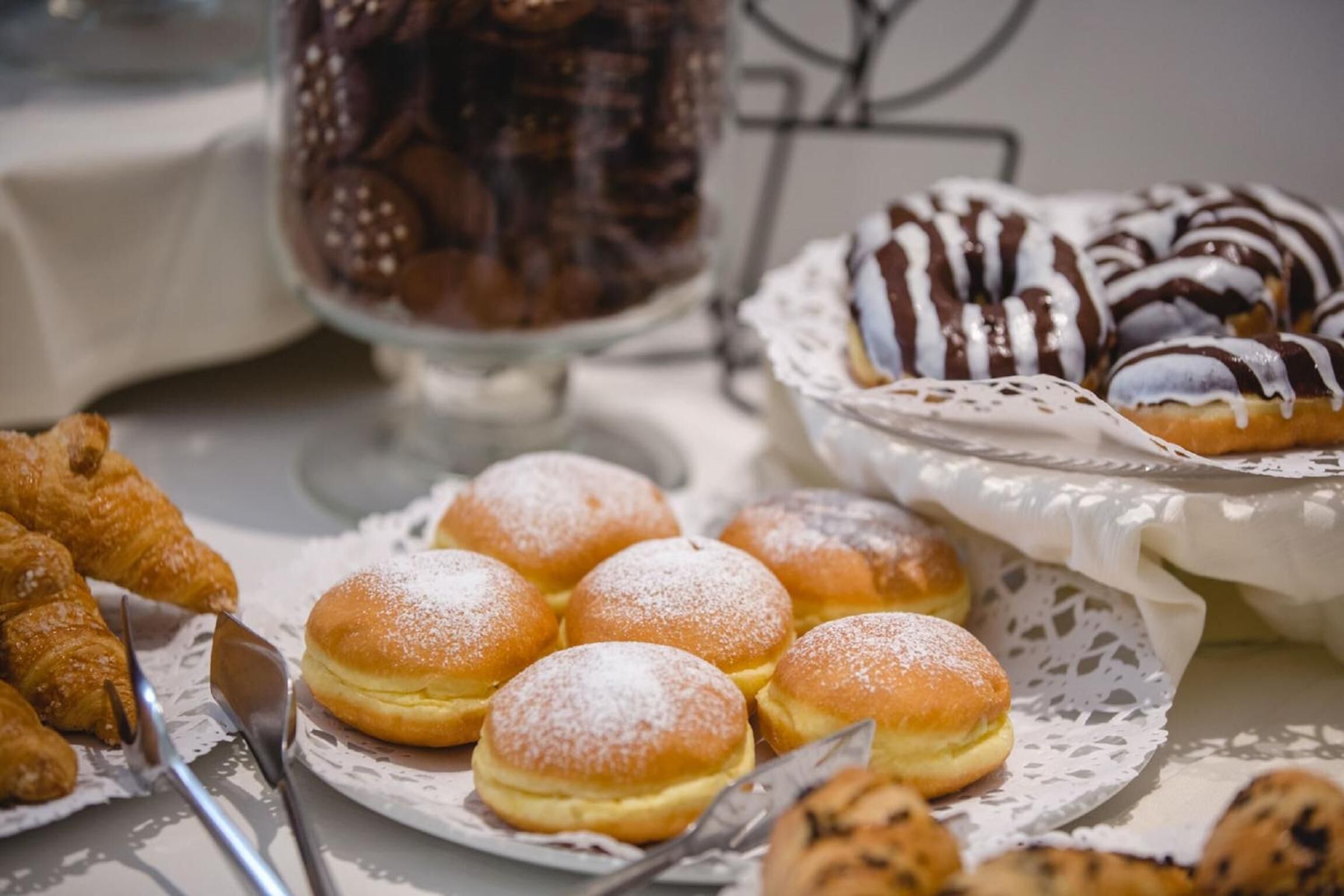 Un tavolo con diversi dolci, tra cui ciambelle, croissant e muffin.