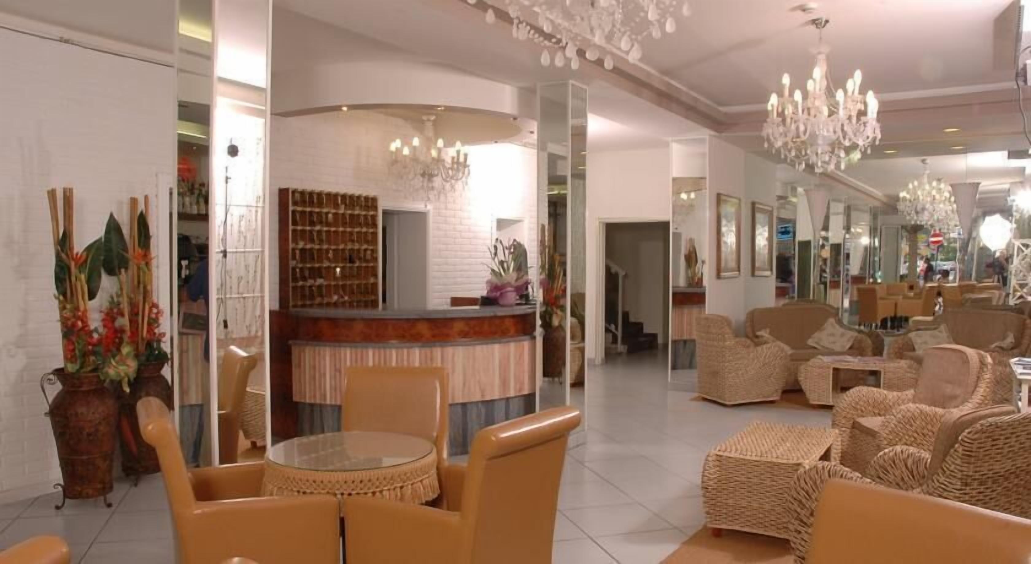 Un vestíbulo amplio con mostrador de recepción, asientos cómodos y plantas decorativas.