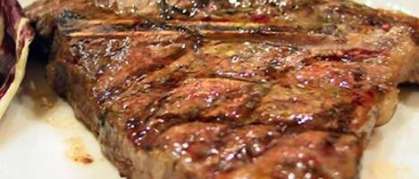 A steak with visible grill marks and a sprig of rosemary on top.