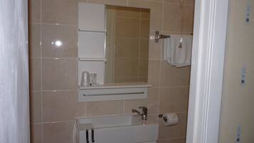 Un baño con lavamanos, espejo y perchero para toallas.