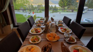 A dining table set for a meal with various dishes, glasses, and a pitcher, overlooking a scenic view of a lake and mountains. - Abant Palace Hotel (Mudurnu)