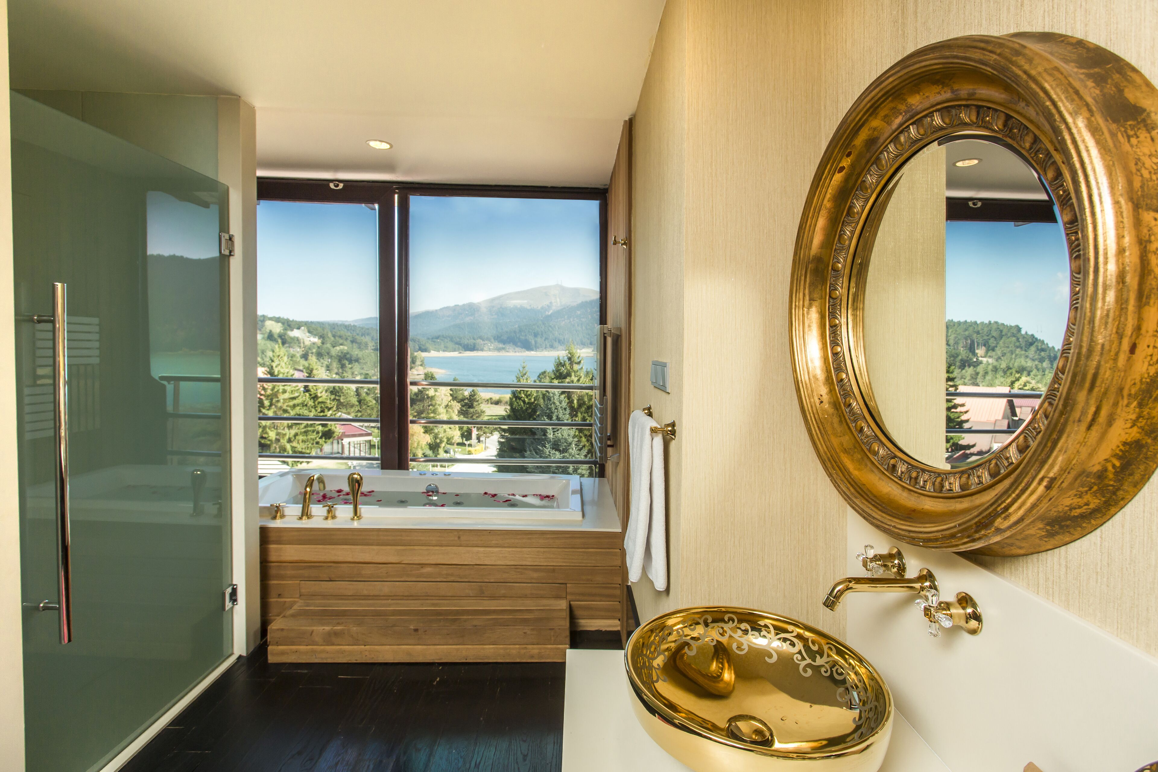 A bathroom with a bathtub, a gold sink, and a large mirror.