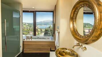 A bathroom with a bathtub, a gold sink, and a large mirror.