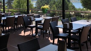 An outdoor dining area with tables and chairs, overlooking a lake and mountains. - Abant Palace Hotel (Mudurnu)