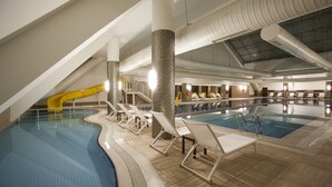 An indoor swimming pool with multiple lanes, a slide, and lounge chairs. - Abant Palace Hotel (Mudurnu)