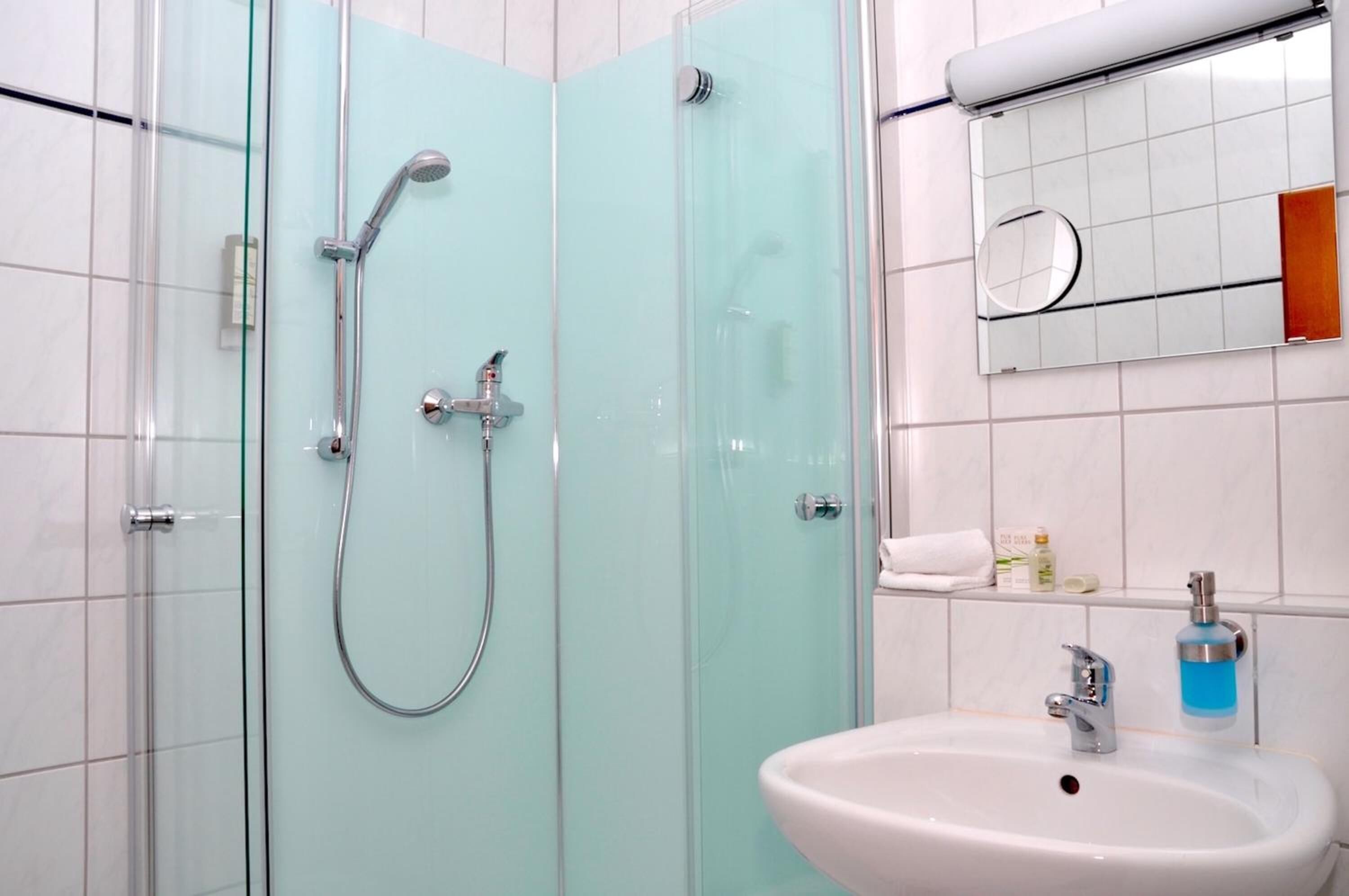 A bathroom with a glass-enclosed shower, a white sink, and a mirror with a wooden frame.