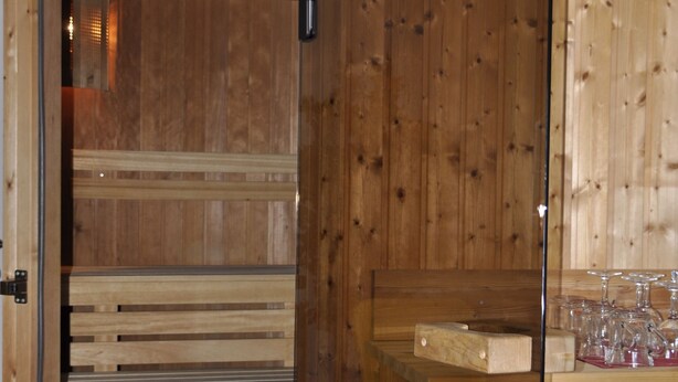 A wooden sauna room with benches and a glass door. - Rennsteighotel Herrnberger Hof (Neuhaus am Rennweg)