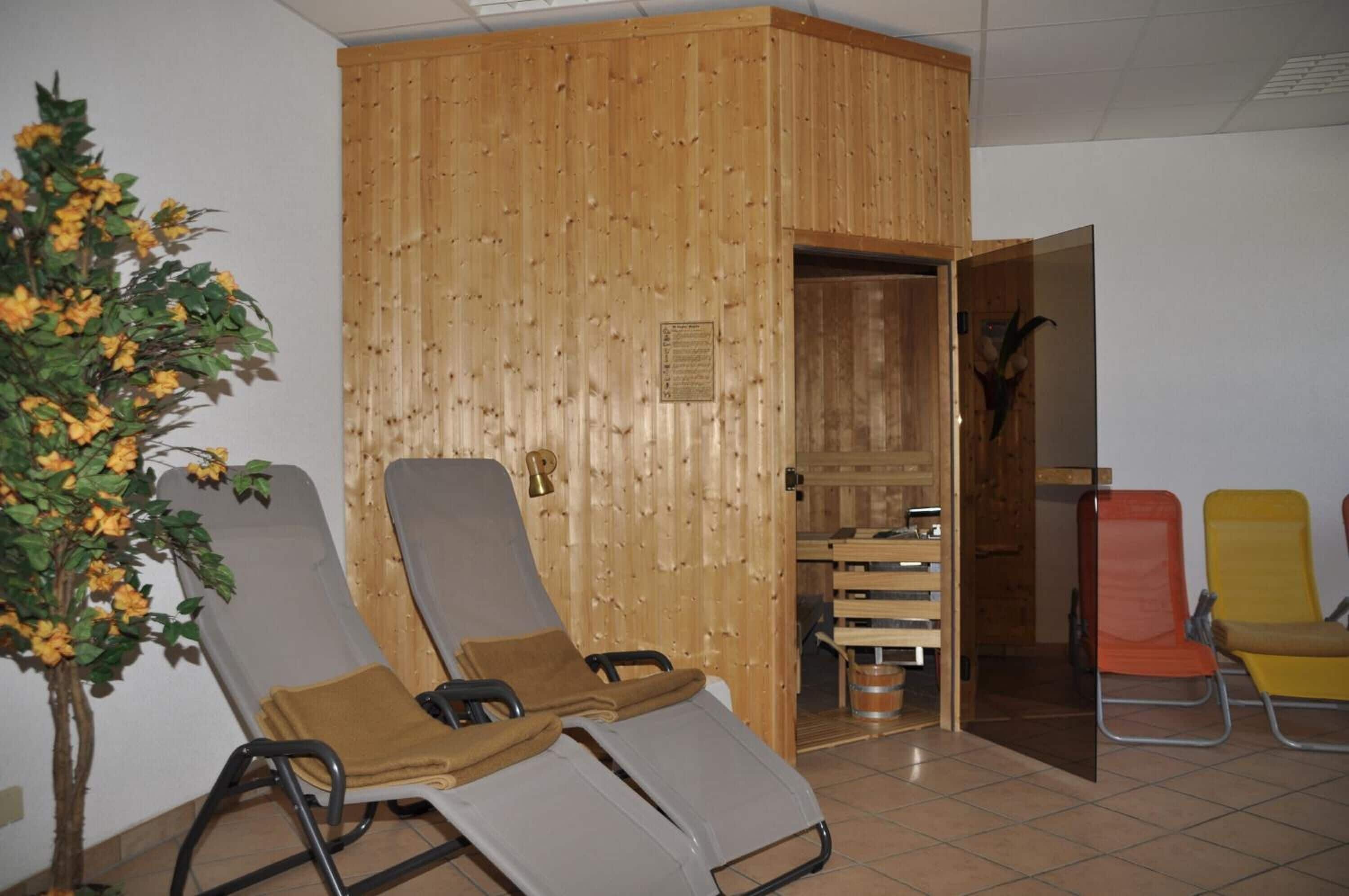 A room with wooden panel walls, a potted plant, and several lounge chairs.