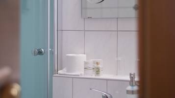 A bathroom with a white sink, a mirror, and a toilet paper holder.