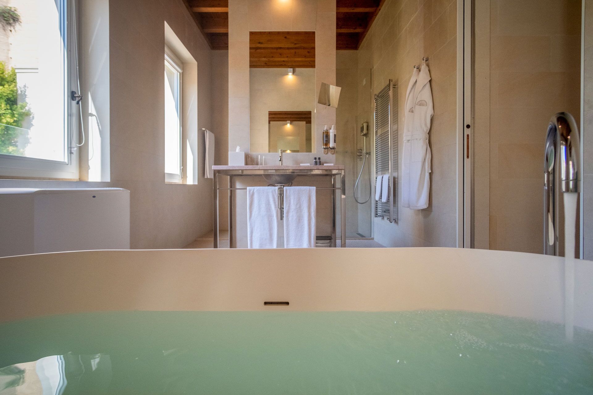 A modern bathroom with a large bathtub, a sink, and a shower area.