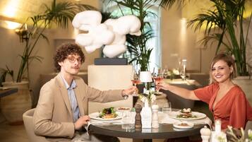Un comedor con una mesa redonda, platos de comida, copas de vino y una escultura decorativa.