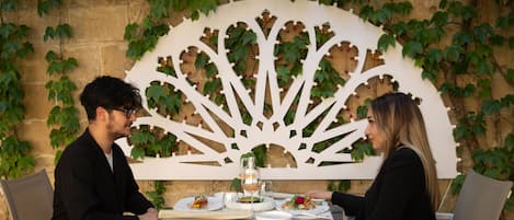 A dining table with plates of food, a wine glass, and a decorative white structure with leaves.
