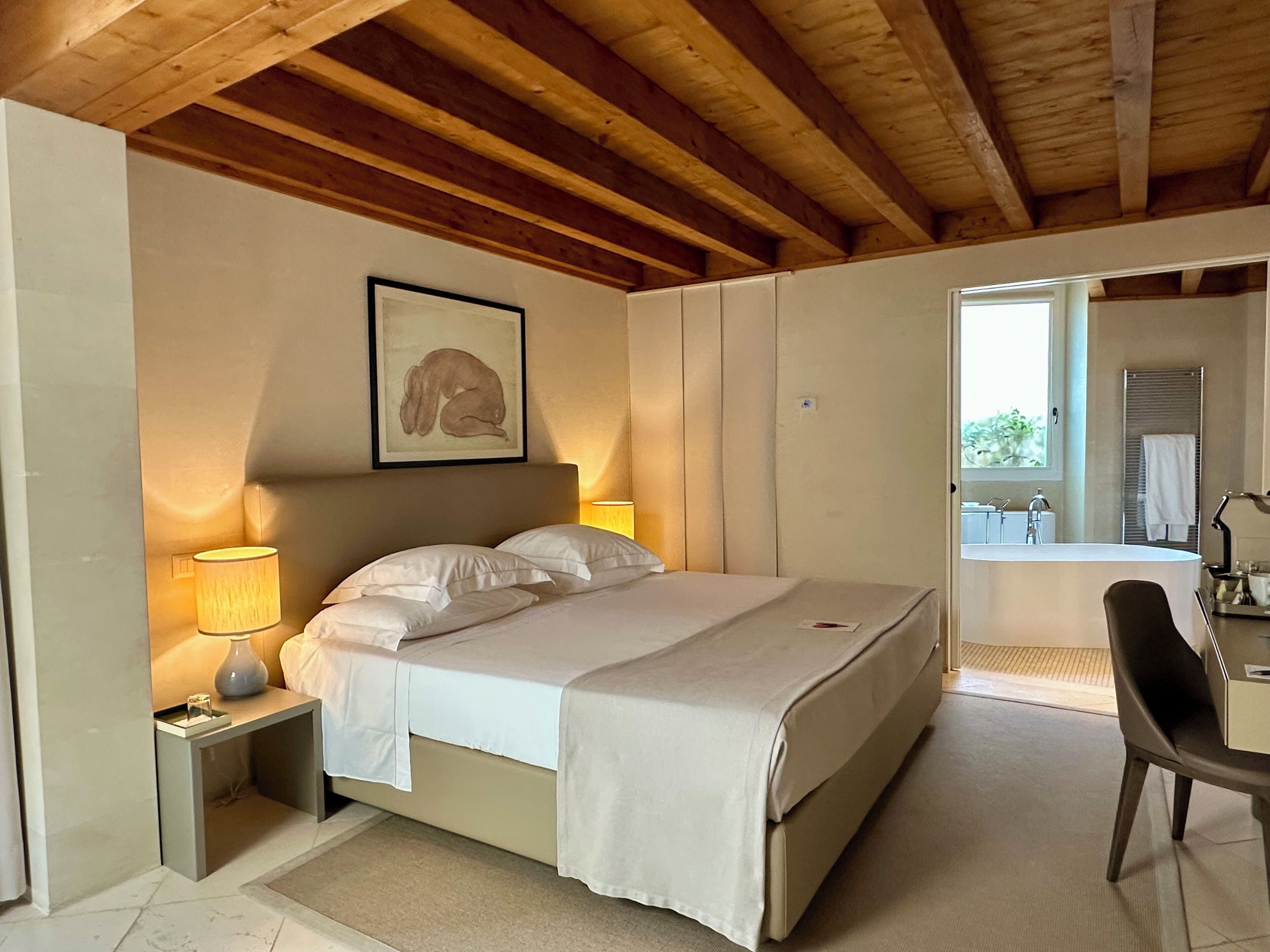 Ein Schlafzimmer mit Bett, Nachttischlampe und einem gerahmten Bild an der Wand.