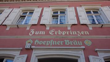 Ein Gebäudefassaden mit der Schrifttafel "Zum Erbpingen" und "hoepfiner Brau", die eine Brauerei kennzeichnet.