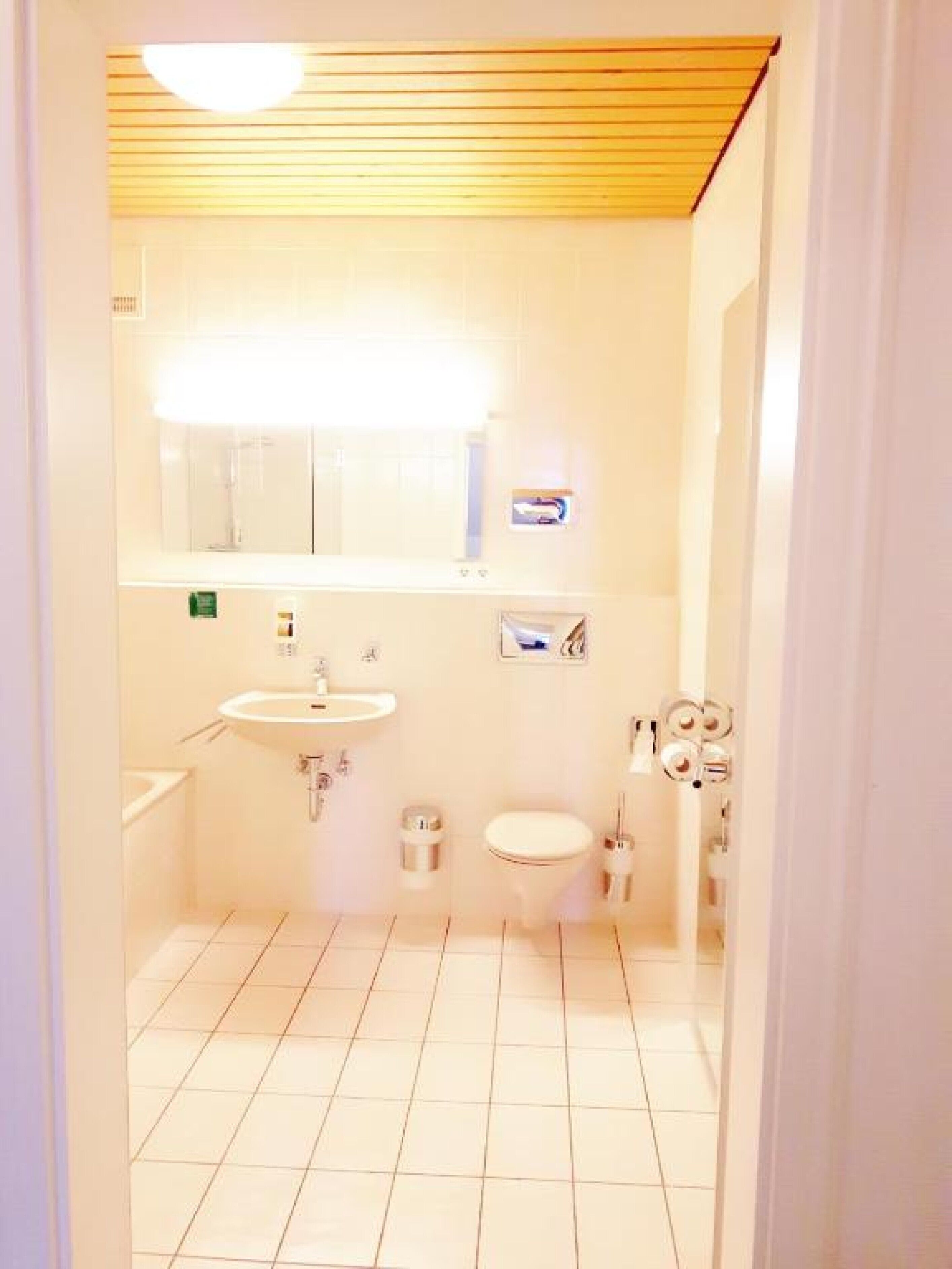 Une petite salle de bain propre, équipée d’un lavabo, de toilettes et d’un miroir.