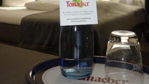 Een fles Teimacher op een dienblad, met een glas in een hotelkamer.