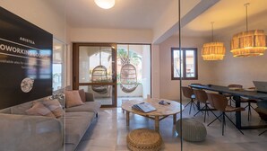 Un espacio de trabajo moderno con un sofá, una mesa redonda y una zona de comedor con sillas.