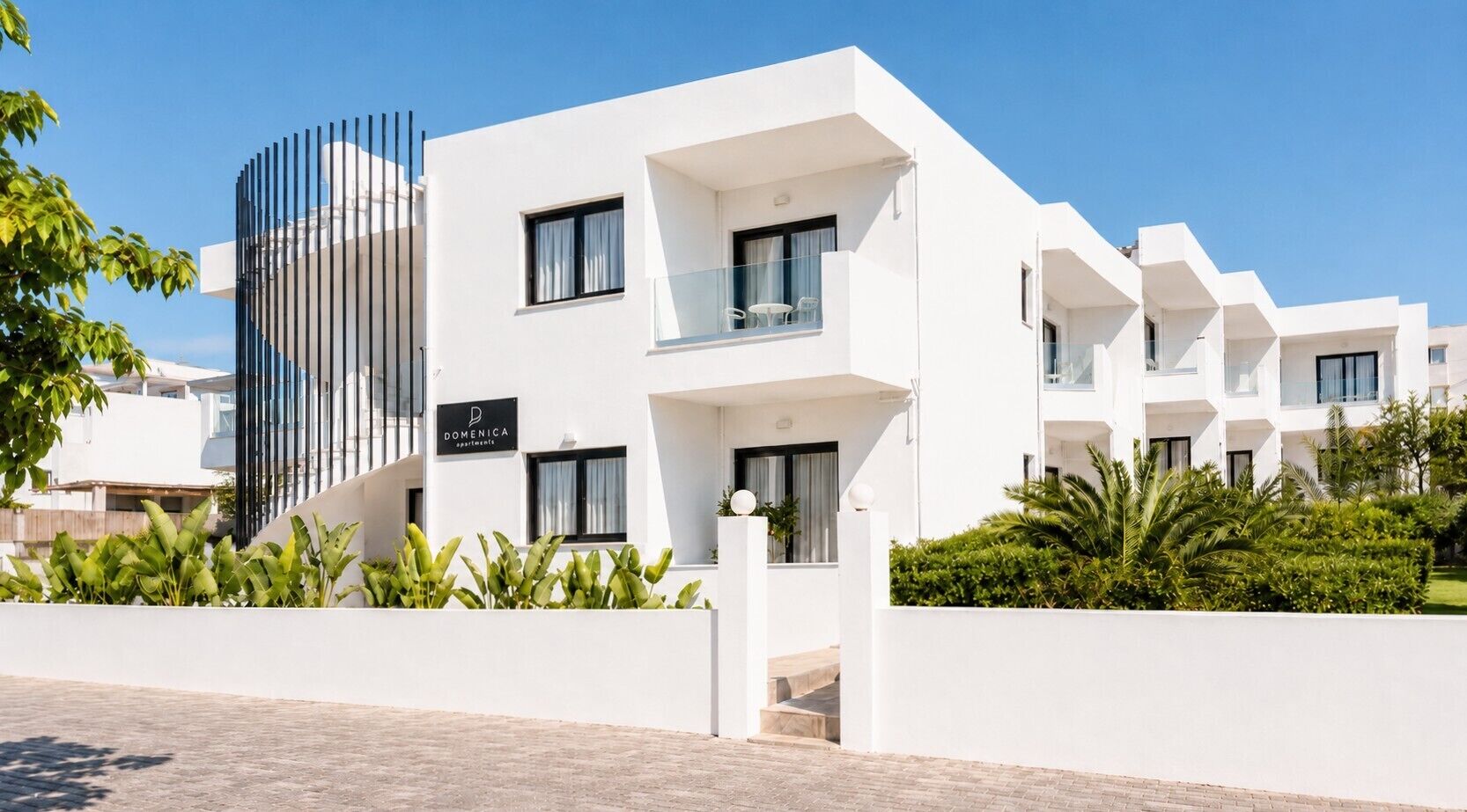 Un hôtel moderne à la façade blanche, doté de balcons et d’une enseigne indiquant qu’il abrite un restaurant.
