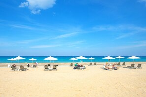 A beach with rows of sun loungers and umbrellas, a clear blue sky, and the ocean in the background. - Domenica Apartments (Rethymno)