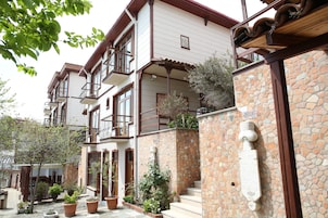 Un edificio de varios pisos con balcones, paredes de piedra y plantas en macetas.