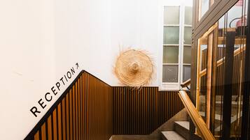 Un área de recepción con pared de madera, una decoración de sombrero de paja y una escalera que conduce a una habitación con ventana.