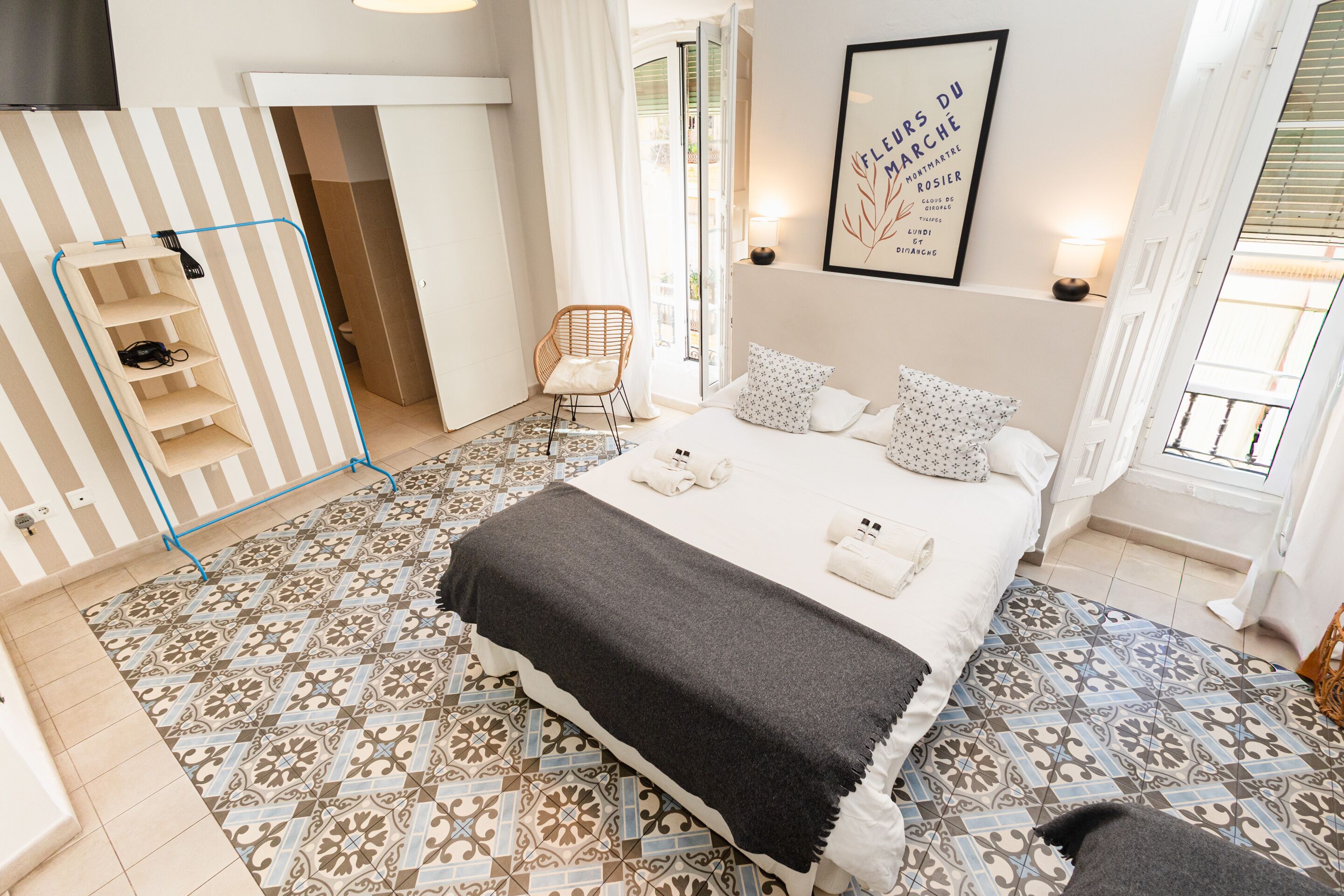 Een slaapkamer met een bed, een stoel, een plank en een deur naar een andere kamer.