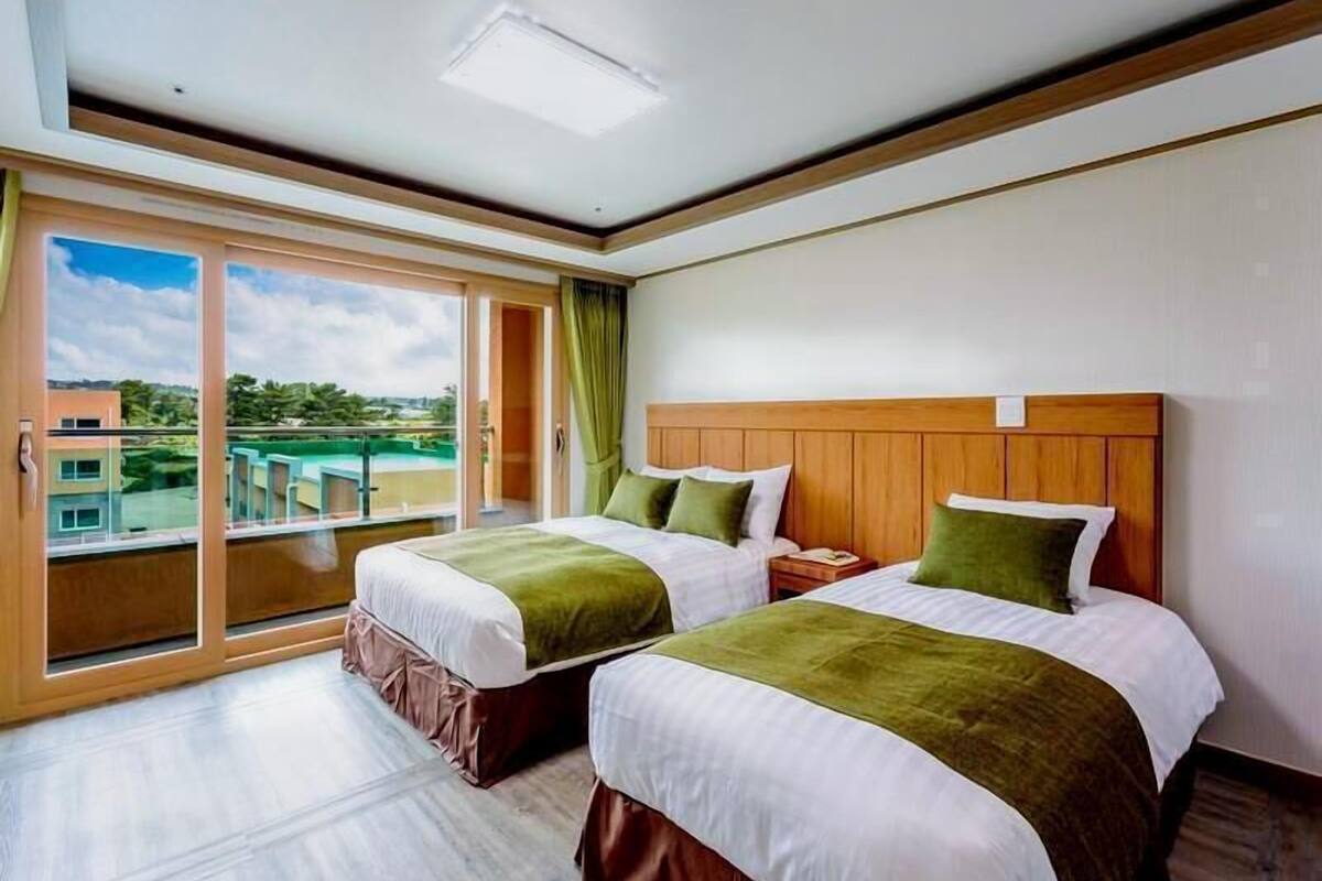 Une chambre d’hôtel avec deux lits, une vue sur la piscine et un balcon.