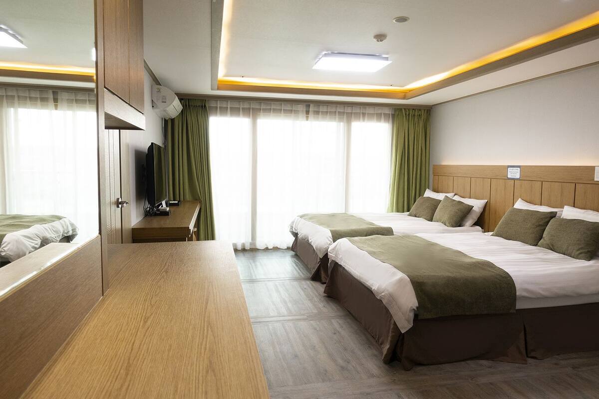Une chambre d’hôtel avec deux lits, un bureau en bois, un téléviseur à écran plat et un grand miroir.