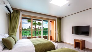 Habitación de hotel con cama, televisor y balcón con vista a palmeras.