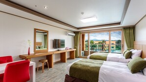 Habitación de hotel con dos camas, un escritorio, televisor y vistas al exterior.