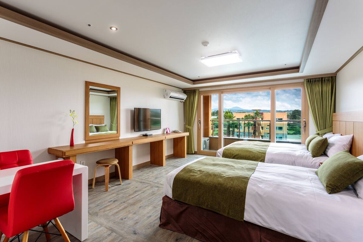 Une chambre d’hôtel avec deux lits, un bureau, une télévision et une vue sur l’extérieur.