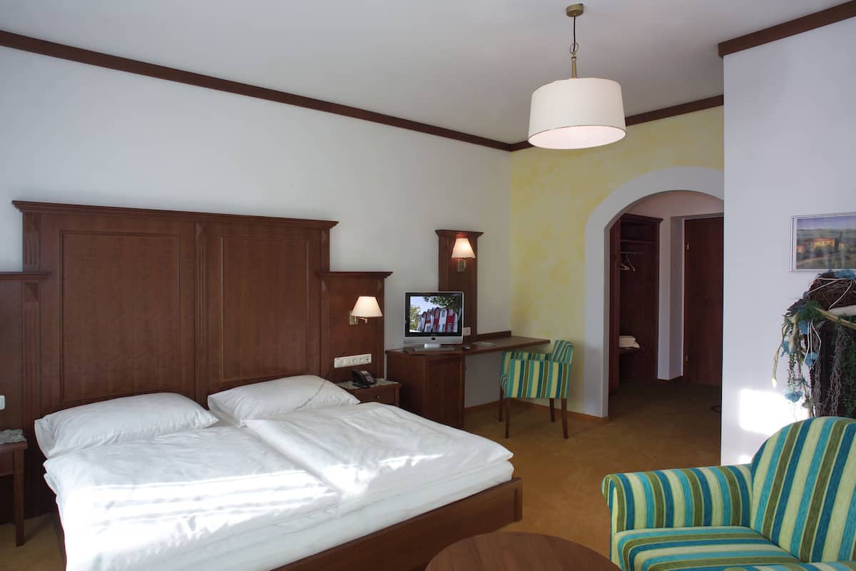 A hotel room with a large bed, a desk with a computer, a chair, and a TV.