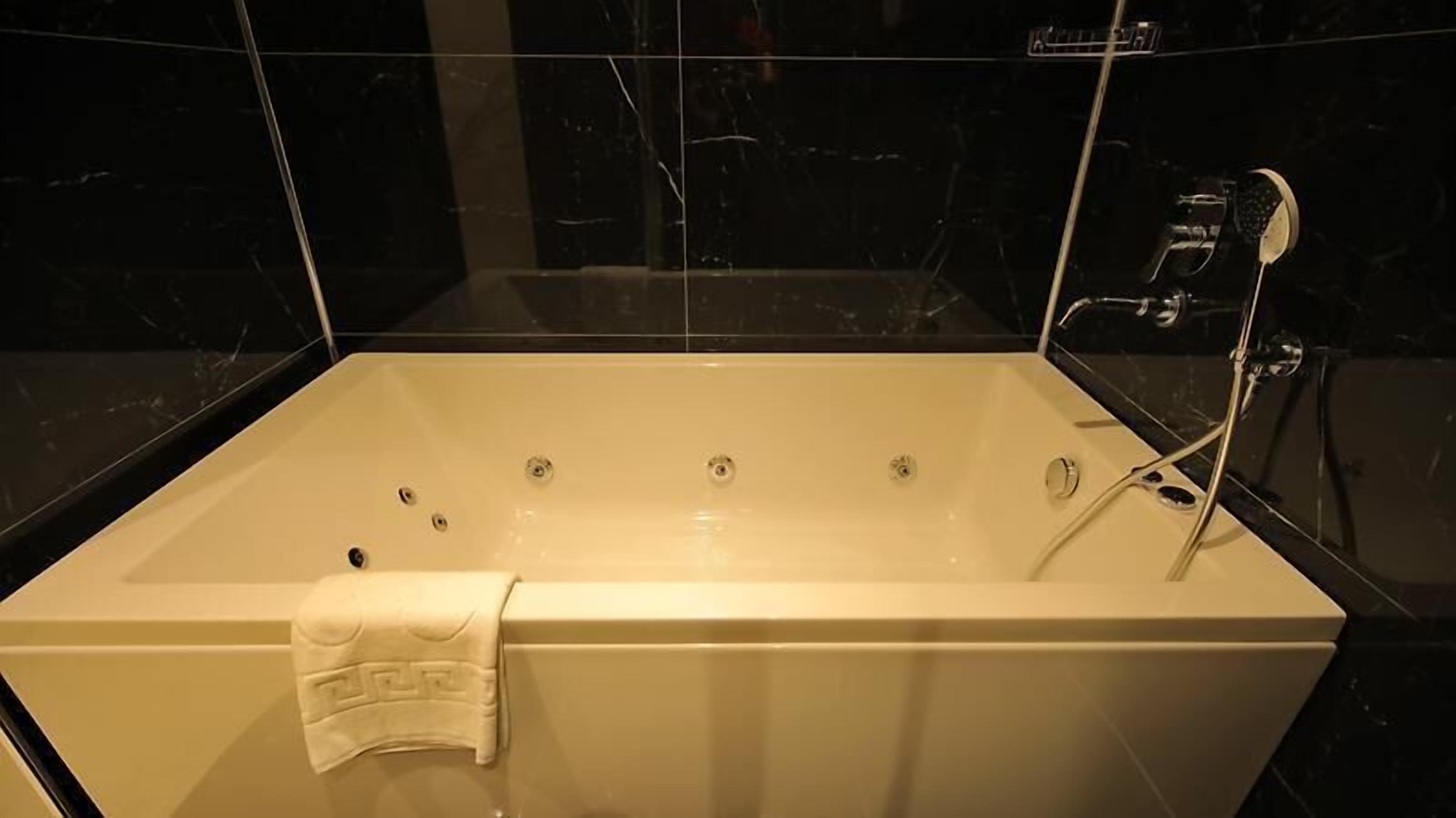 Una bañera grande y rectangular con una toalla blanca colgada al lado.