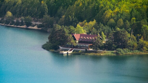 A lakeside cabin with a red roof, surrounded by dense forest, and accessible by a small dock. - Abant Kosk (Mudurnu)
