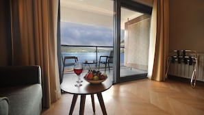A room with a view of a lake, a table with a fruit bowl and a glass of red wine, and a chair. - Abant Kosk (Mudurnu)