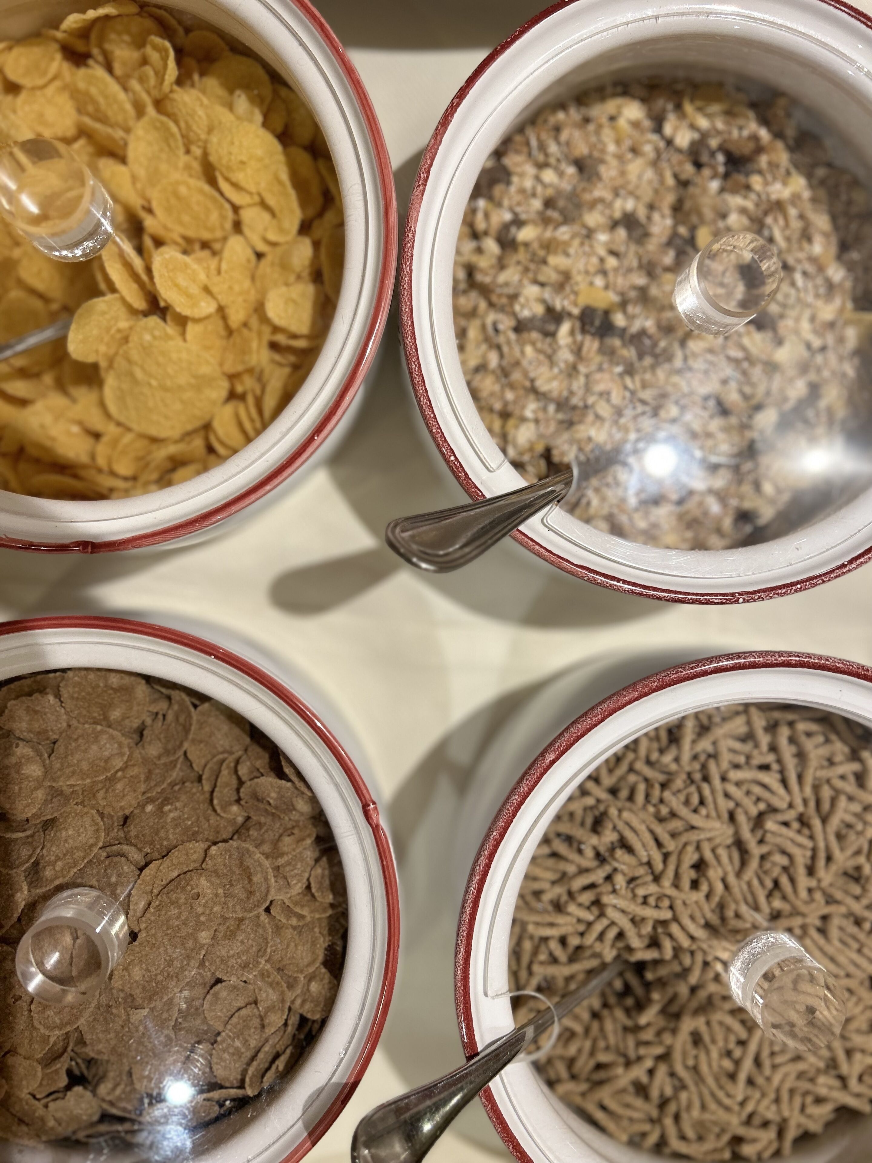 Four bowls of cereal with spoons.