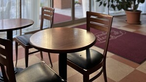 A café with round tables and chairs, large windows, and a potted plant. - Hotel Due Torri Tempesta (Noale)