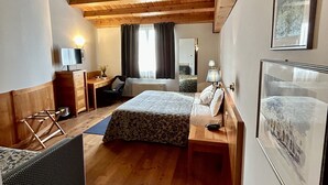 A bedroom with wooden beams on the ceiling, a bed with a patterned bedspread, a bedside table with a lamp, and a framed picture on the wall. - Hotel Due Torri Tempesta (Noale)