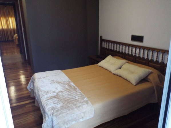 A bedroom with a bed, wooden headboard, and a bedside table. - Hotel Ansuiña (Banos De Molgas)