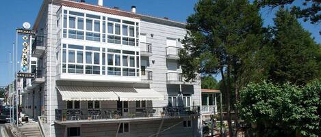 Un bâtiment à deux étages, doté d’un restaurant et d’une enseigne d’hôtel, et comprenant un balcon avec des places assises extérieures.