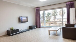 Una sala de estar moderna con un televisor de pantalla plana montado en la pared, una mesa de centro de madera y un sofá oscuro.