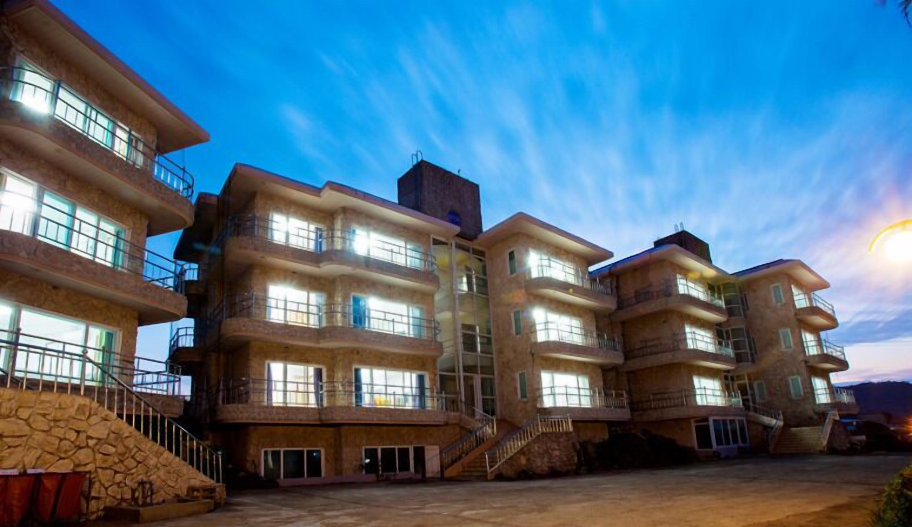 A multi-story hotel with balconies, a stone facade, and a clear sky.