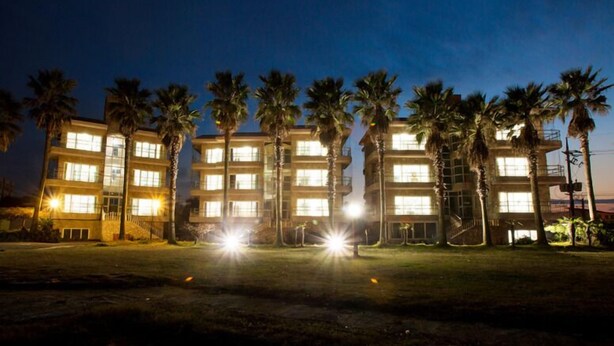 Un hotel de varios pisos con ventanas iluminadas y palmeras en primer plano.