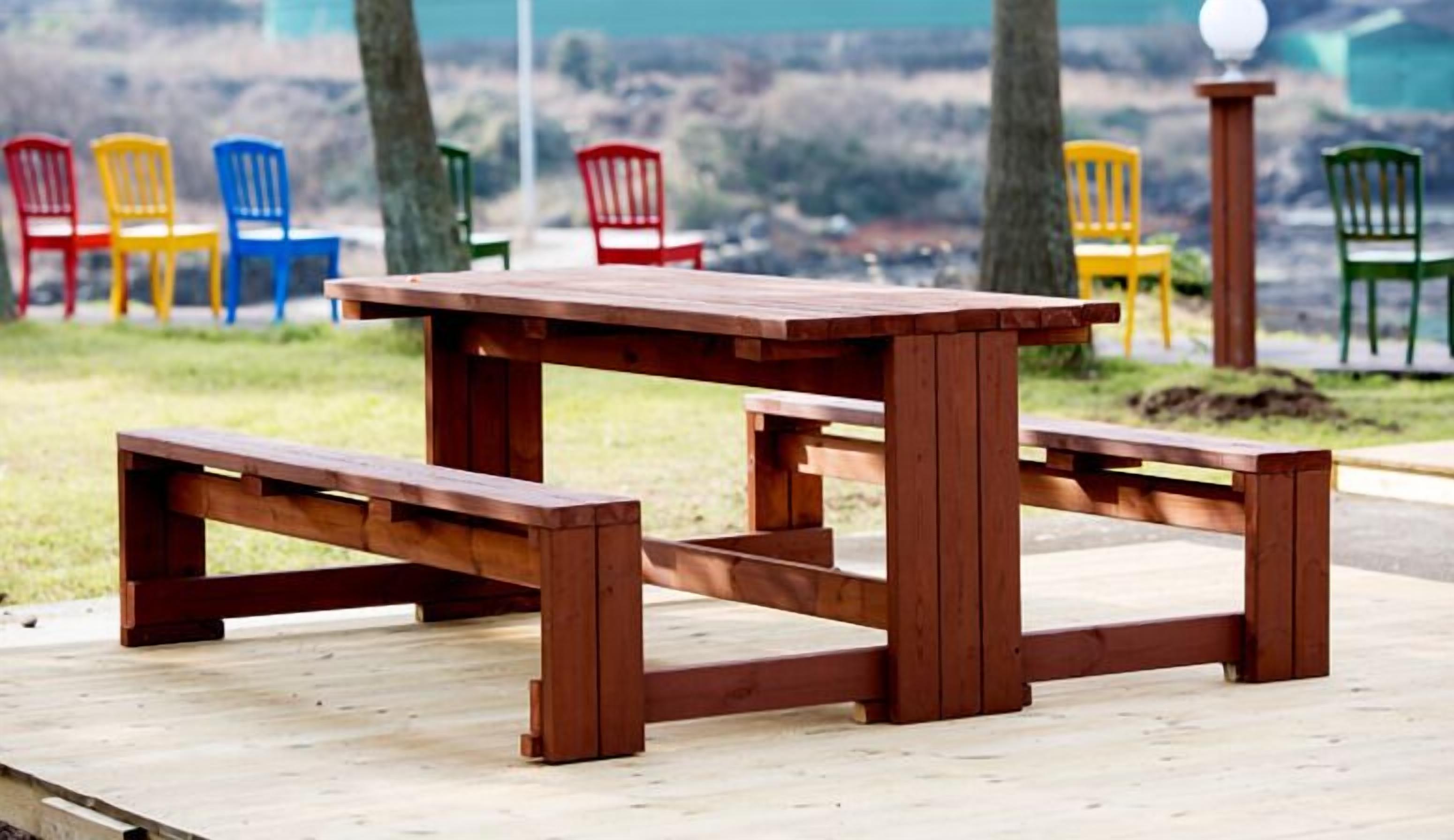 A wooden picnic table with benches in a park setting.