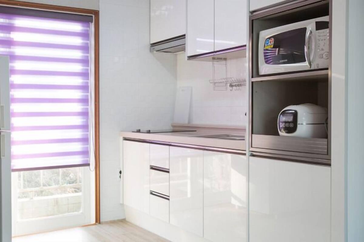 A modern kitchen with white cabinetry, a microwave, and a toaster.