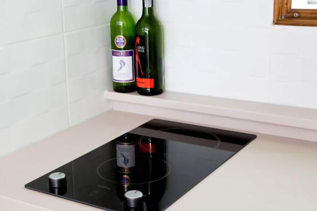 A kitchen with a built-in induction cooktop and a wine bottle on the counter.