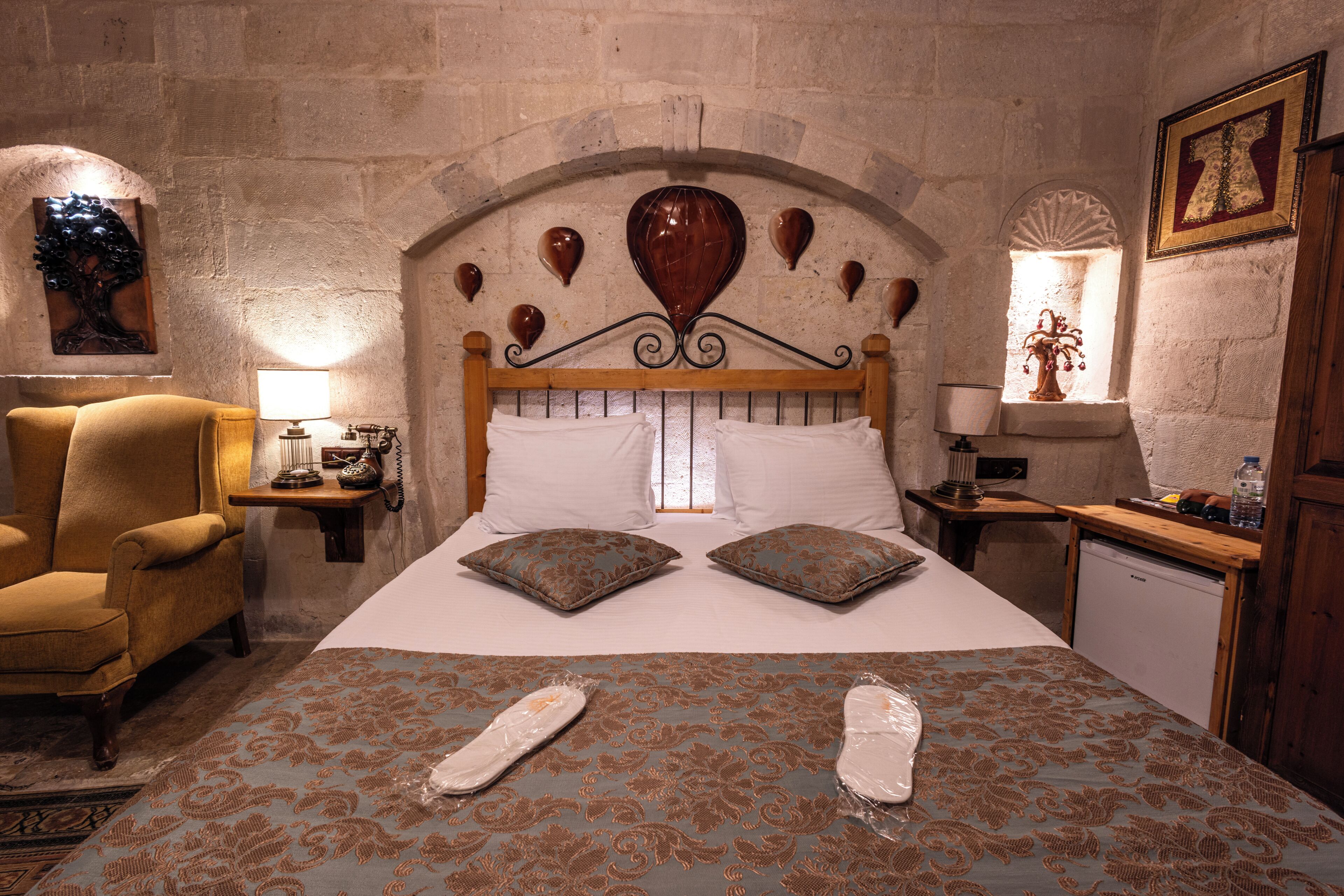 A bedroom with a large bed, a wooden headboard, a chair, a nightstand, and a small table with a lamp.