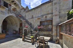 Un patio con escaleras de piedra, muebles de madera y plantas en macetas.